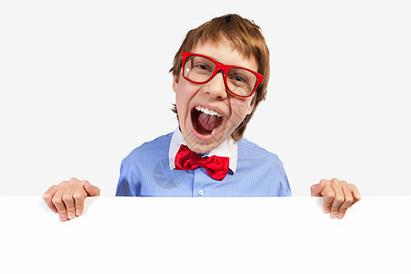 红色戴红眼镜的男孩持有白方广告牌海报手臂领结框架手指微笑眼镜快乐学生图片