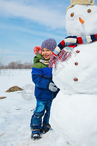 男孩做雪人衣服活动娱乐院子帽子微笑童年乡村闲暇场景图片