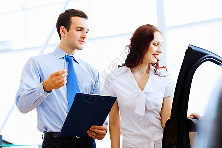 在汽车沙龙的年轻女子兜帽夫妻经销商合同驾驶女性租赁销售员顾问服务图片