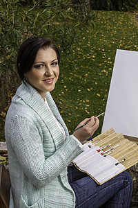 年轻女子在公园上画画成人刷子闲暇画笔女性艺术爱好帆布享受艺术家图片