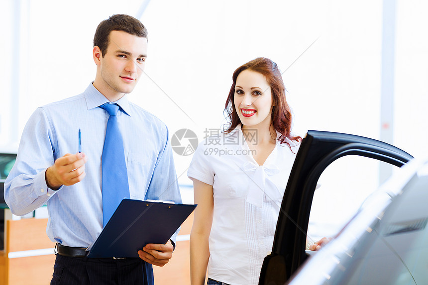 在汽车沙龙的年轻女子租赁推销员顾问销售合同经销商驾驶夫妻客户销售员图片