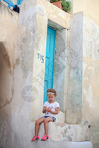 坐在希腊桑托里尼Emporio村旧房子台阶上的可爱的小女孩住宅历史性农村建筑楼梯假期家庭村庄脚步婴儿图片