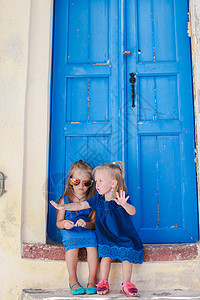 坐在圣托里尼希腊Emporio村旧蓝门附近的可爱小女孩图片