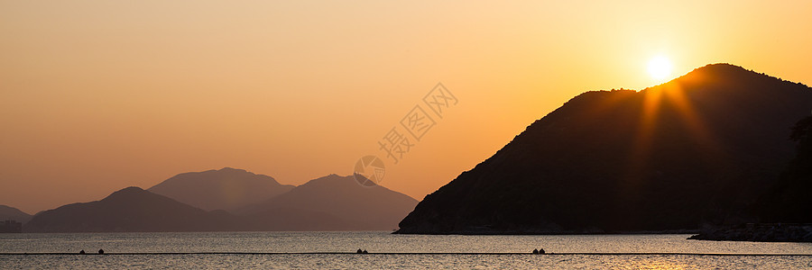 日落时海和山丘图片