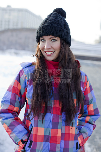 冬季城市背景中一位年轻女性的肖像街道雪花外套黑发幸福手套薄片季节衣服享受图片