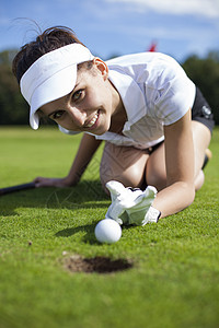 在草地上打高尔夫的漂亮女孩游戏推杆闲暇运动玩家课程女孩爱好男人遮阳棚图片