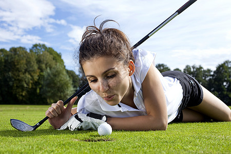 漂亮女孩在高尔夫球场作弊男人爱好场地推杆女孩运动游戏微笑女士高尔夫球图片