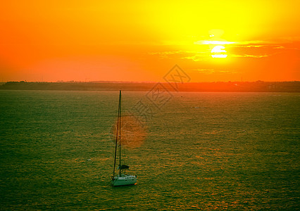 美丽的海日落帆船热带地平线橙子旅行反射天空太阳游客游艇图片