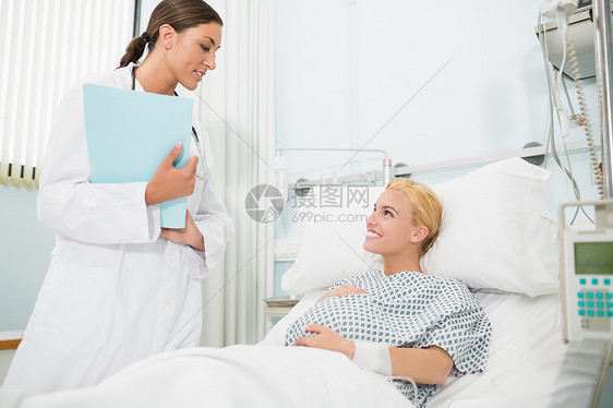 产科医生与一个微笑的怀孕病人交谈图片
