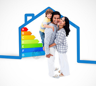 微笑的家庭站在一个蓝色房子插图和能源评级图表的蓝房子旁图片