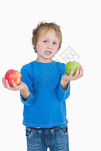 年轻男孩的肖像 握着绿色和红苹果图片