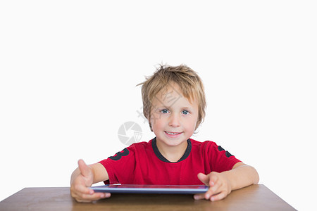 坐在桌上的带数字平板电脑的小男孩的肖像背景图片