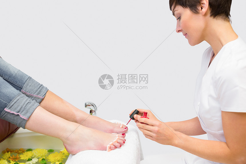 女性在温泉中心施用指甲清漆的脚趾指甲美容美容师治疗双手束腰成人美甲师美容院分隔器美甲图片
