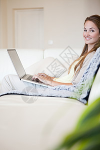 在沙发上使用笔记本电脑的临时妇女肖像图片