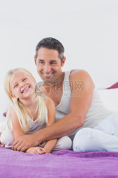 父亲和女儿在床上微笑 坐在床上图片
