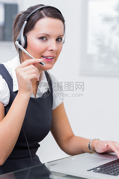 在服务台使用膝上型电脑时佩戴头盔的女性行政主管技术呼叫头发人士桌子沟通操作员中心商务女士图片