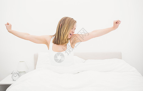睡着的女人在床上拉伸双臂时打哈哈哈哈图片