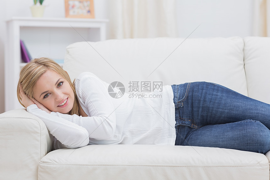 躺在沙发上的临时妇女肖像牛仔裤闲暇长椅头发客厅家庭生活金发女性房子图片