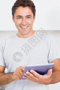 微笑的人用平板电脑 pc快乐触摸屏房子住所男人棕色公寓家庭厨房头发图片