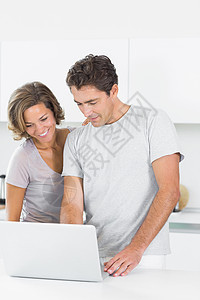 使用笔记本电脑一起微笑的情侣夫妻家庭柜台房子女士女性头发技术成人住所图片