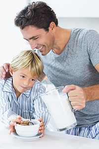 微笑的父亲为儿子倒牛奶谷类图片