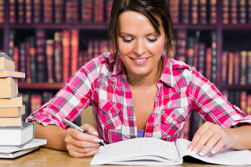 带着一本书微笑的女孩倾斜书架长发女士快乐文学女性大学作业头发图片