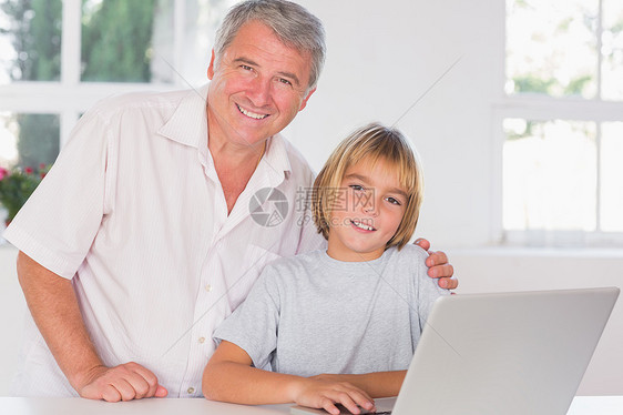 祖父和孩子在笔记本电脑前微笑地看着摄像机图片