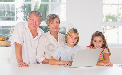 孩子们和祖父母在前面用笔记本电脑一起看相机图片