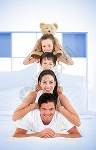 微笑的家庭在床上靠着彼此的肩膀快乐枕头男生住所坐垫女士卧室男性男人公寓图片