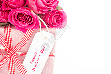 紧贴着一束粉红玫瑰的花束 旁边是一份粉红礼物 上面有快乐的母亲日卡图片