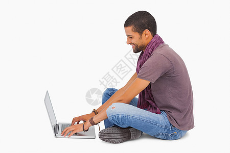 男人用笔记本电脑坐在地板上时戴围巾图片