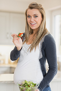 孕妇吃沙拉孕妇装女性腹部头发家长台面女士怀孕微笑健康饮食背景图片