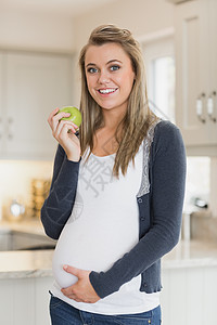 持有苹果的怀孕妇女长发孕妇装金发女郎家长母亲腹部金发快乐台面食物图片