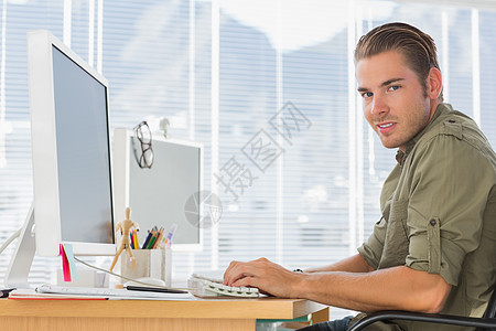 微笑从事计算机工作的创造性商业雇员; 在电脑上工作图片