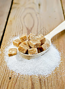 黑板上一个勺子中的糖 棕色糖和颗粒糖背景图片