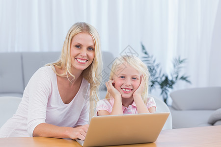 母亲与女儿使用笔记本电脑微笑图片