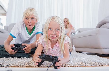 玩电子游戏的兄弟姐妹闲暇女性儿子对抗竞赛房子女孩小地毯男性金发女郎图片