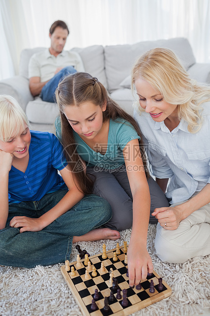 坐在地毯上玩象棋的兄弟姐妹和母亲图片