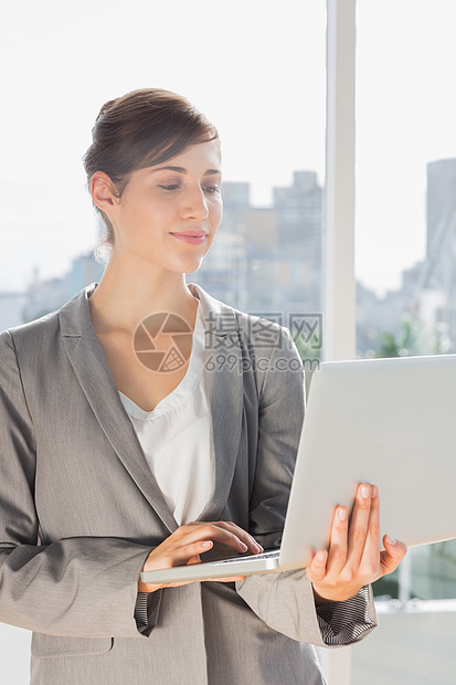 从事笔记本电脑的漂亮商业妇女工作办公室技术公司职场快乐女士套装商务人士图片