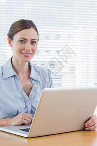 漂亮的女商务人士对着镜头微笑女性人士女士公司工作办公室头发衬衫技术棕色图片