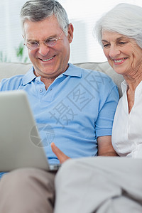 夫妇在沙发上用笔记本电脑夫妻白色房子男性快乐岁月女士头发亲密感流金图片