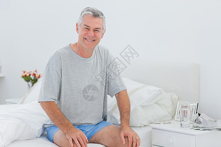 男人坐在床上时笑着微笑图片