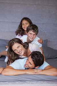 微笑的家庭一起在床上玩耍图片