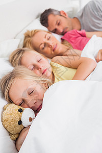 年轻女孩在睡梦中家庭旁边抱着泰迪熊图片