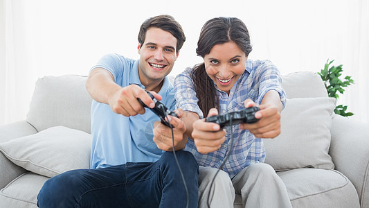 一对夫妇在沙发上玩电子游戏头发休息室房子客厅控制器混血夫妻公寓长发快乐图片