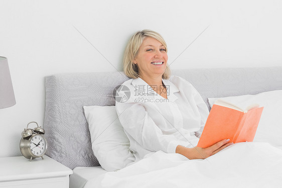 坐在床上看书的开心女人图片
