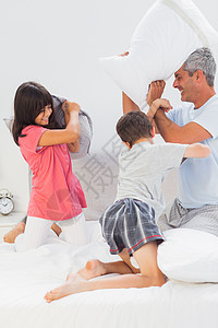 父亲和他的孩子在床上与枕头并肩作战图片