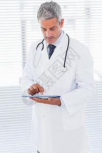使用平板电脑的医生药片触摸屏短发微笑头发从业者男人医院办公室医务室图片