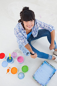 快乐的女士坐在地板上涂着油漆图片