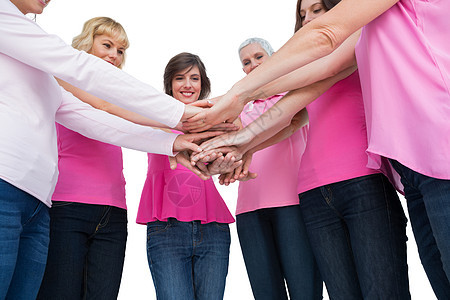 穿着粉红色乳癌胸衣的重身妇女围成圈 手举手看着照相机图片